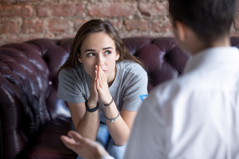 Youth sitting on couch talking to adult Youth sitting on couch talking to adult