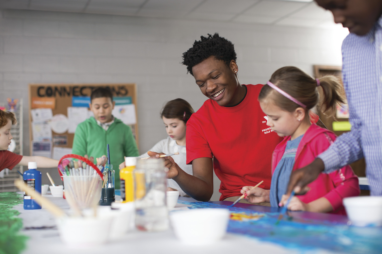 YMCA children laughing together while painting