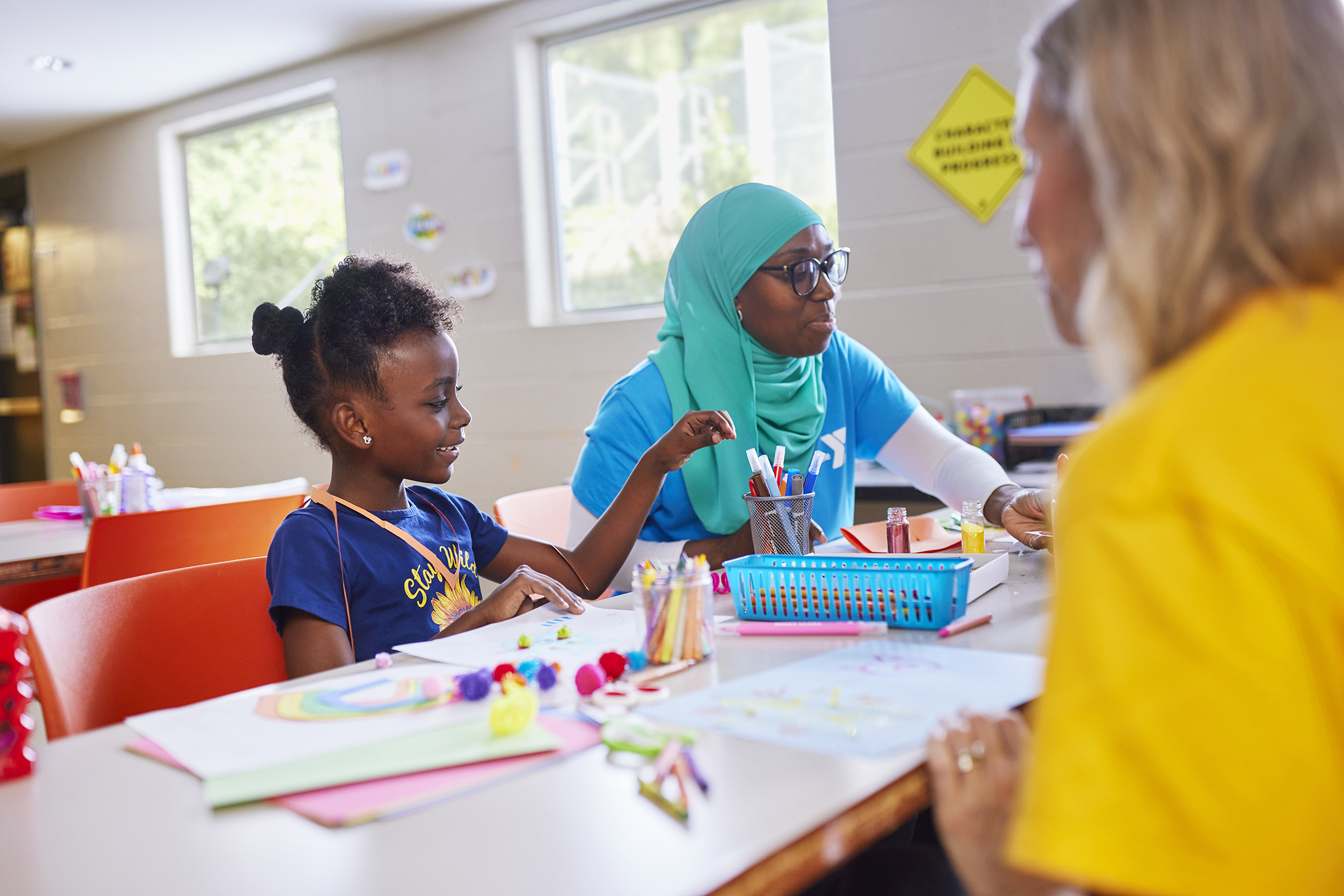 Child and YMCA staff member making a craft