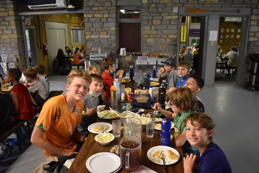 Kids and teens gathered around a table eating a meal at Camp Piomingo Kids and teens gathered around a table eating a meal at Camp Piomingo