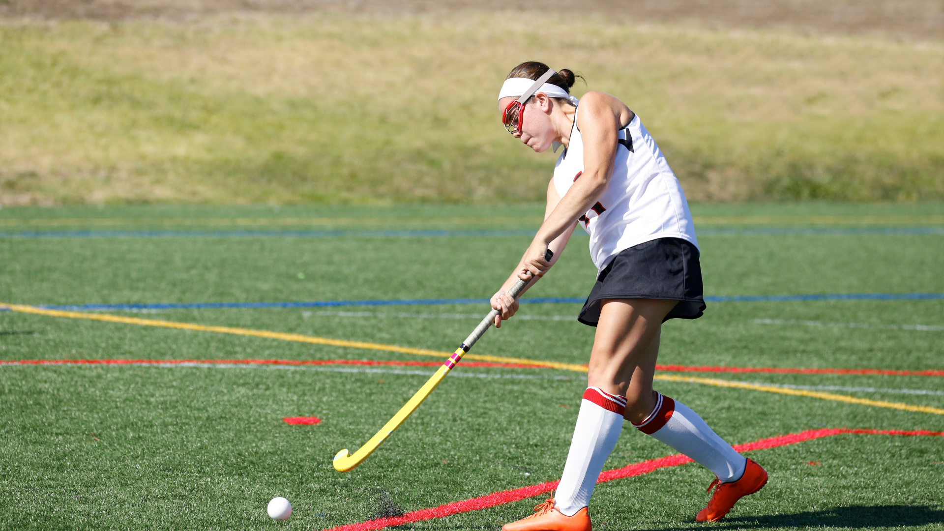 Teen swinging her field hockey stick at a puck