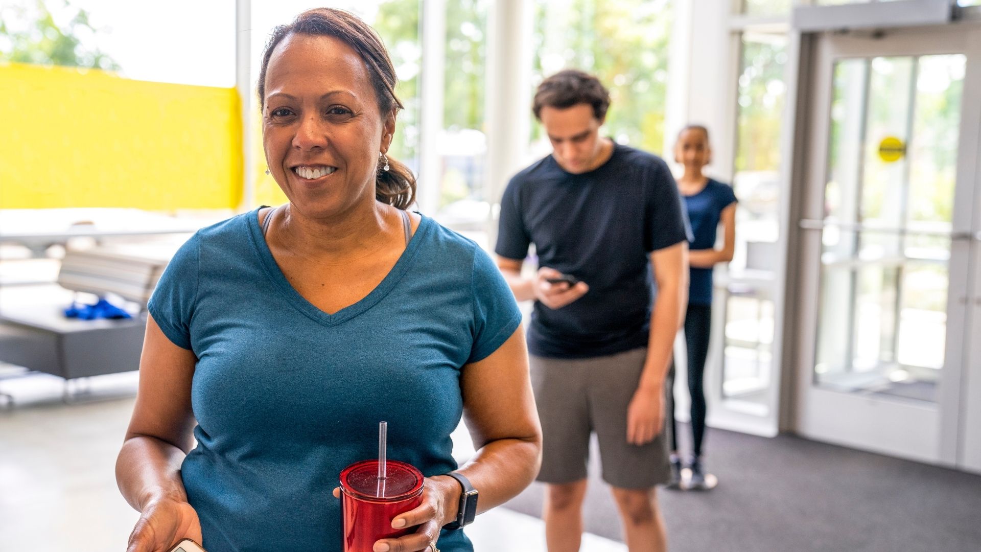 Smiling woman walking into YMCA facility ready to check in