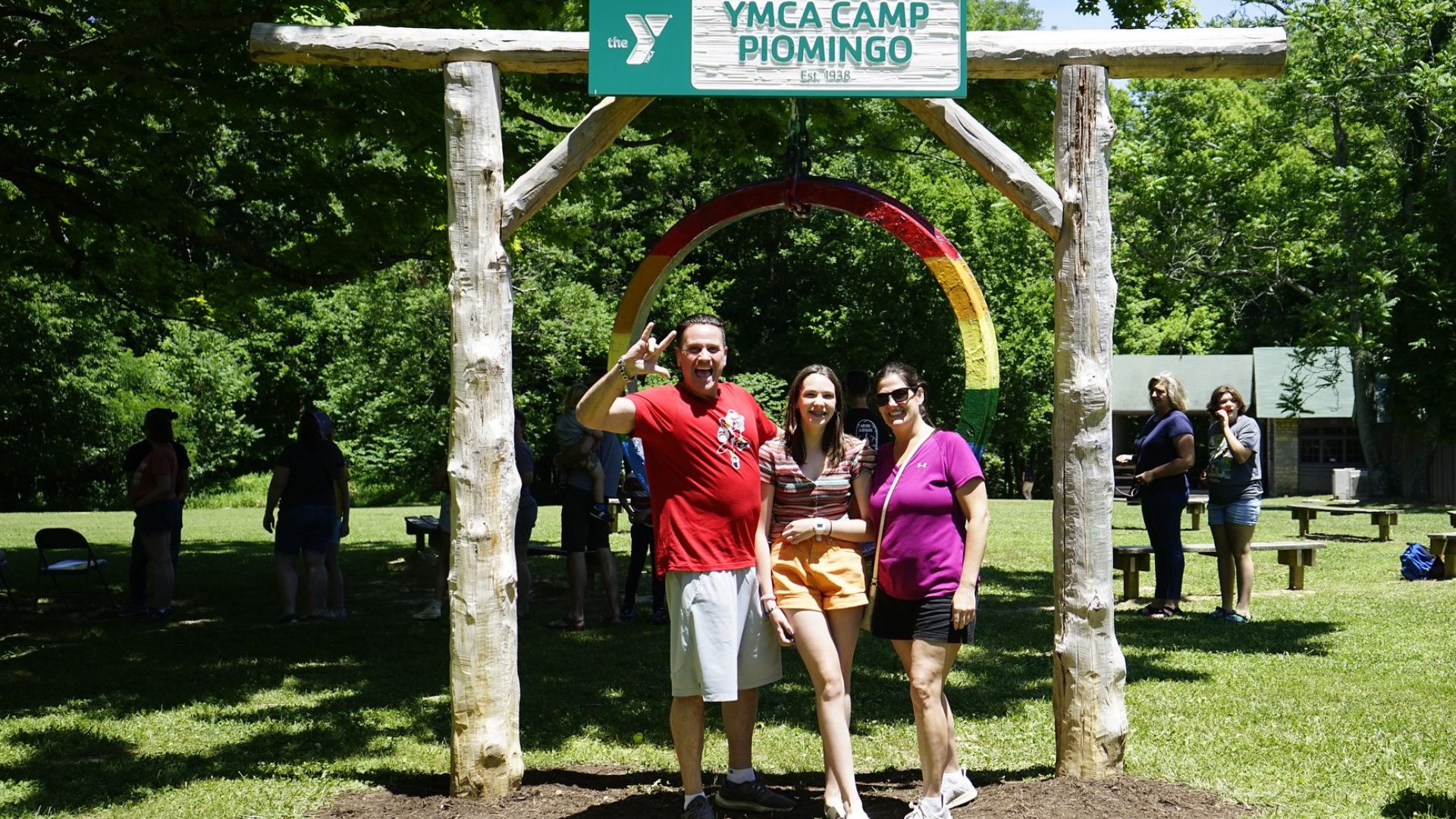 Family standing together in front of the YMCA Camp Piomingo gong Family standing together in front of the YMCA Camp Piomingo gong