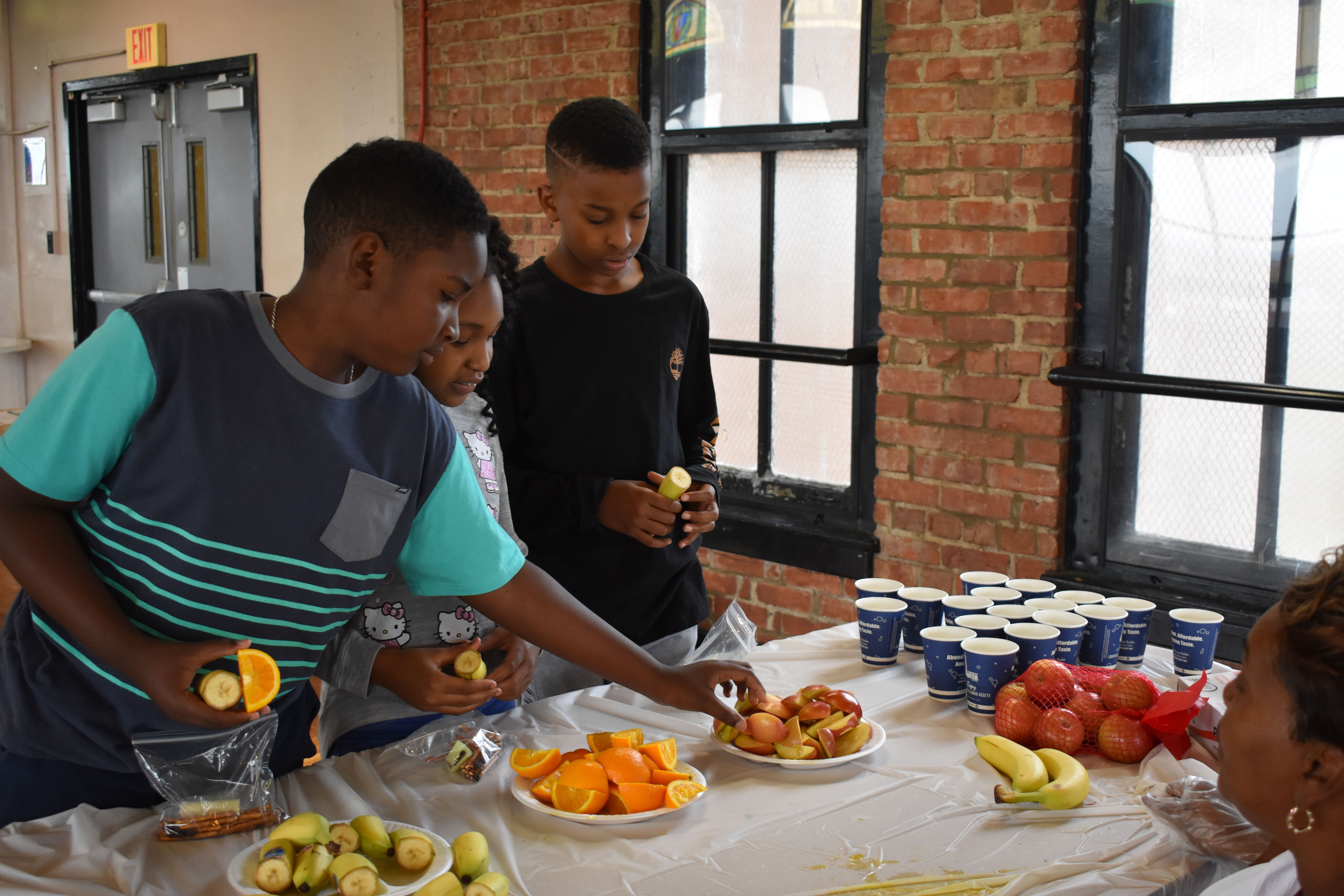 Group of boys at table with fruit Group of boys at table with fruit