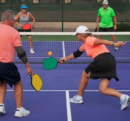 Group of four older adults playing pickleball outdoors