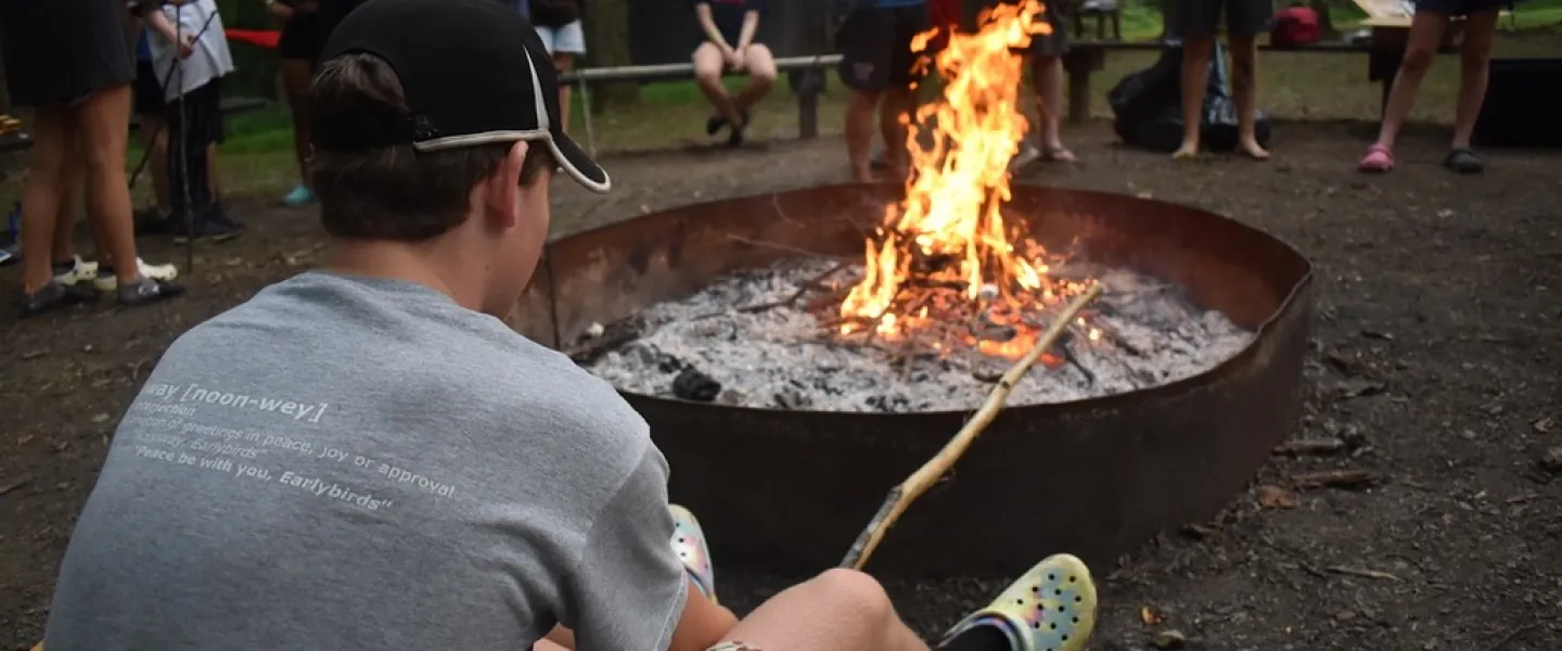 Camper roasts smores over the fire pit at YMCA Camp Piomingo