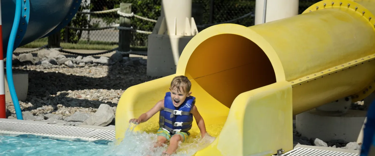 Child sliding down a water slide at YMCA Louisville Calypso Cove Waterpark