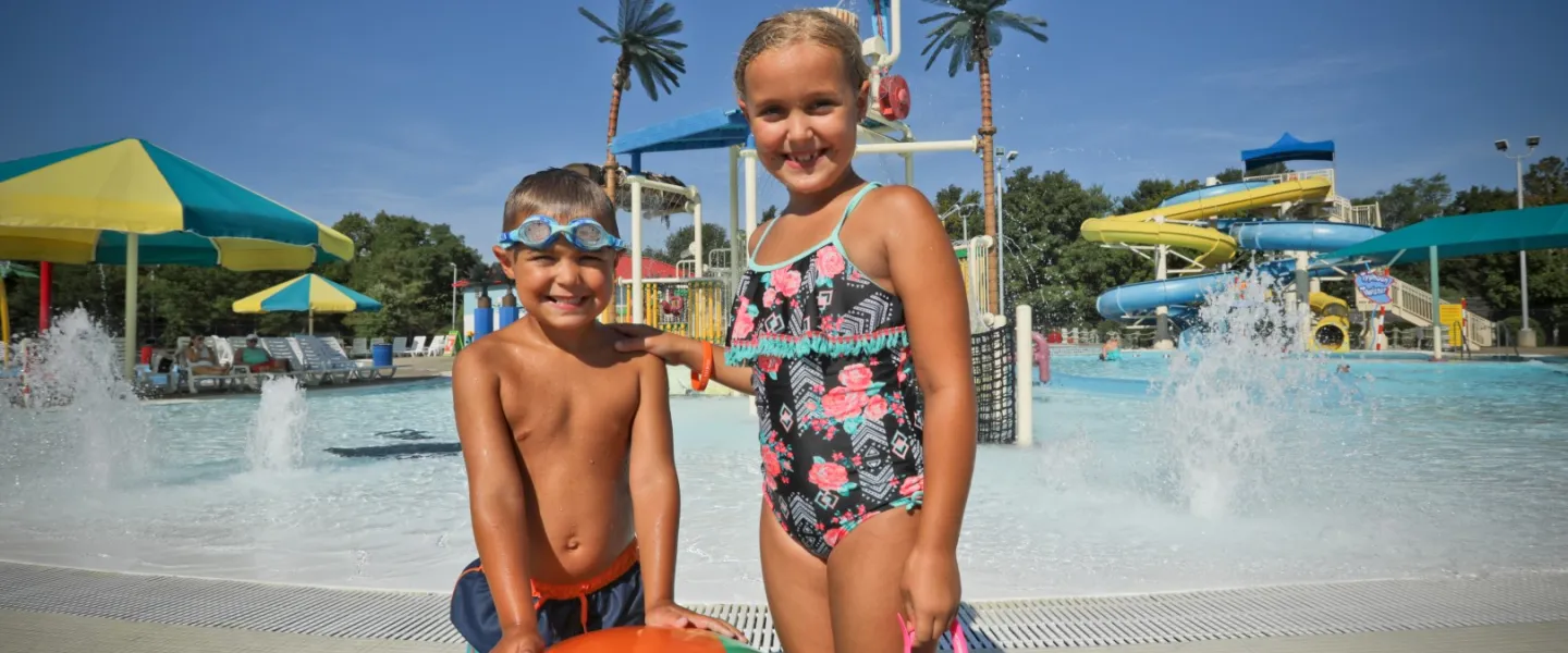 Three kids posing in front of Calypso Cove Waterpark interactive play structure