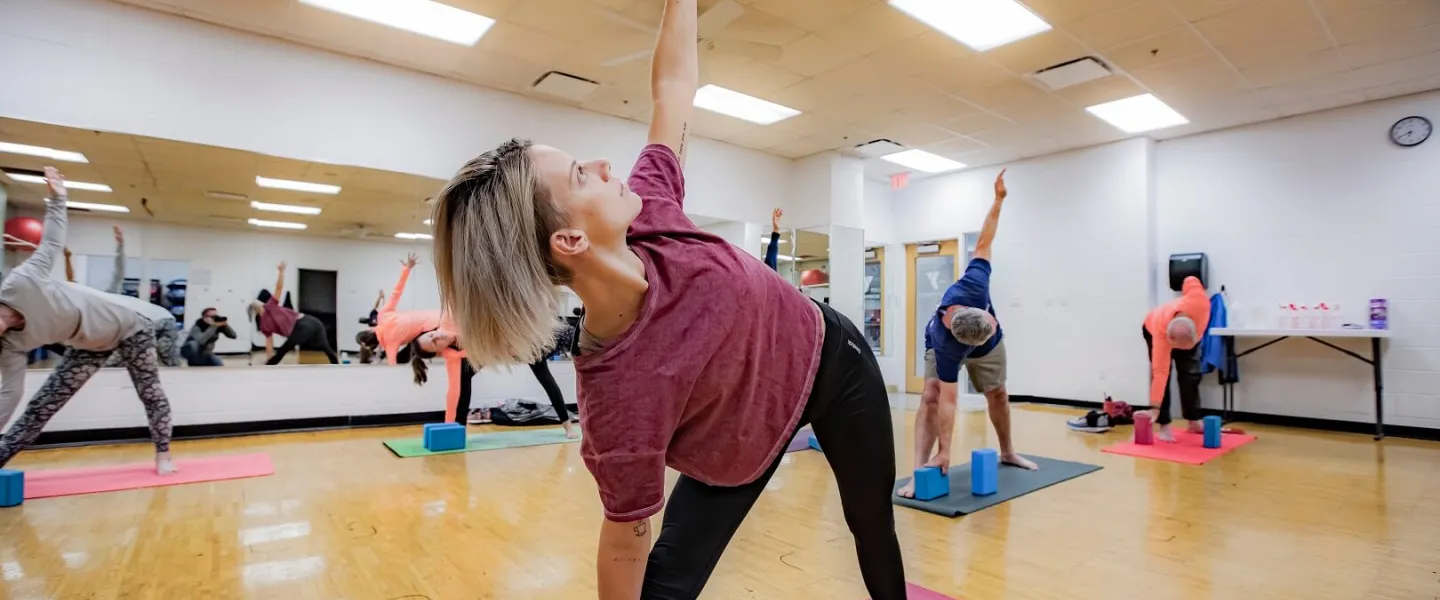 Adults doing yoga pose at group mind and body class at YMCA Louisville