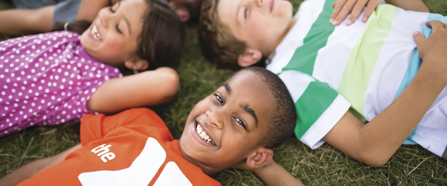 Group of kids laying on the ground looking at clouds