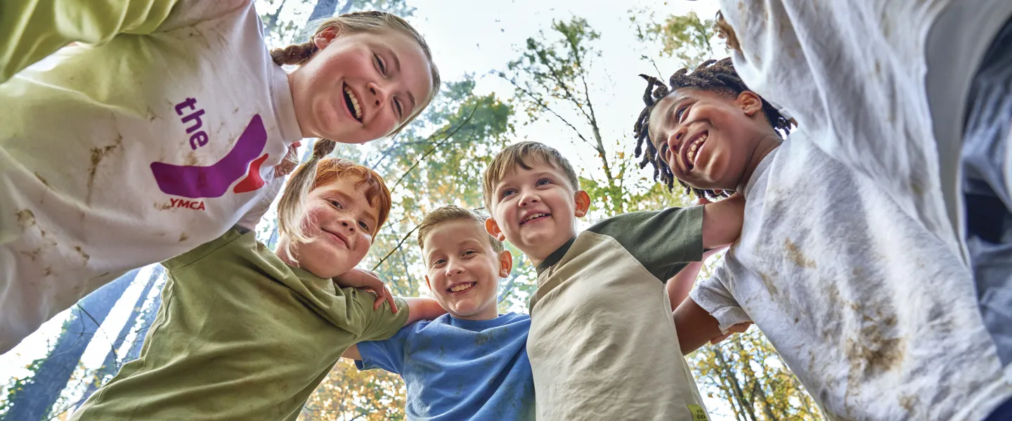 Group of kids outdoors in a circle smiling