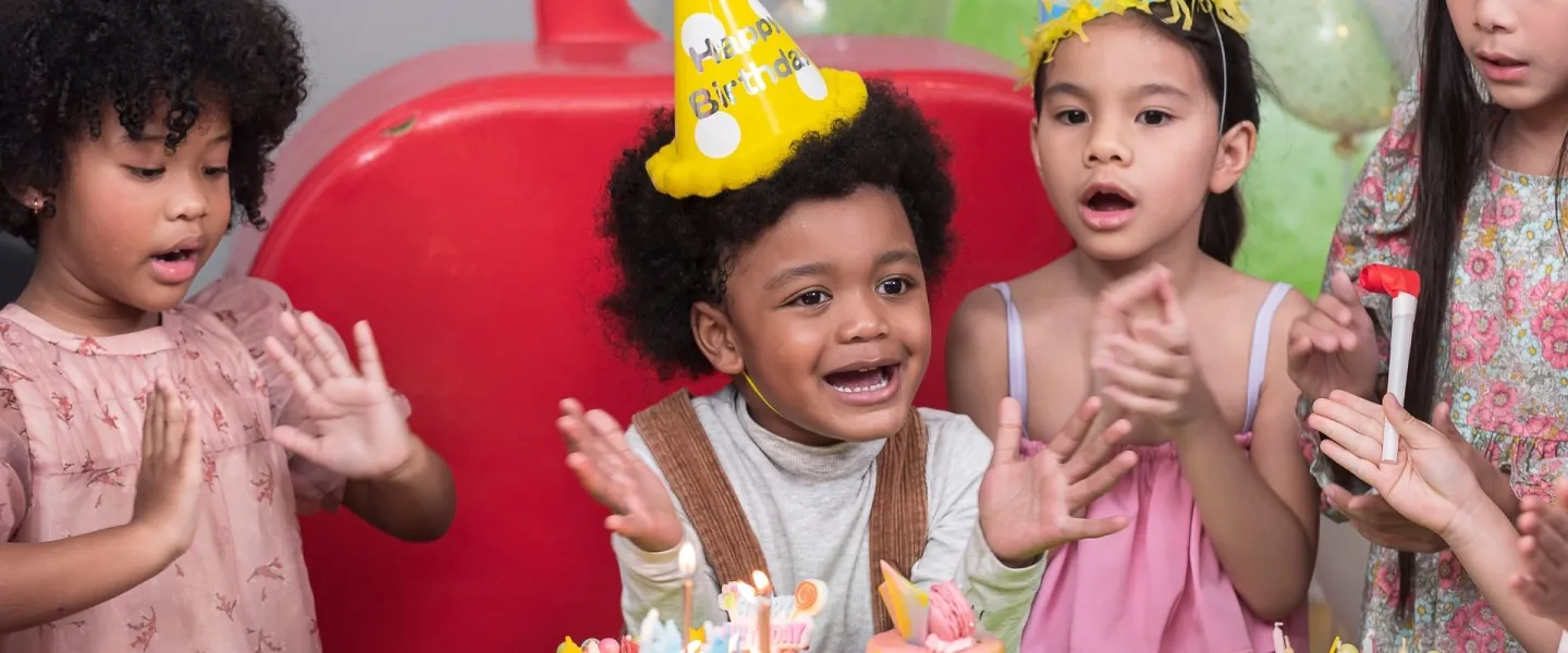Group of kids in party hats clapping hands