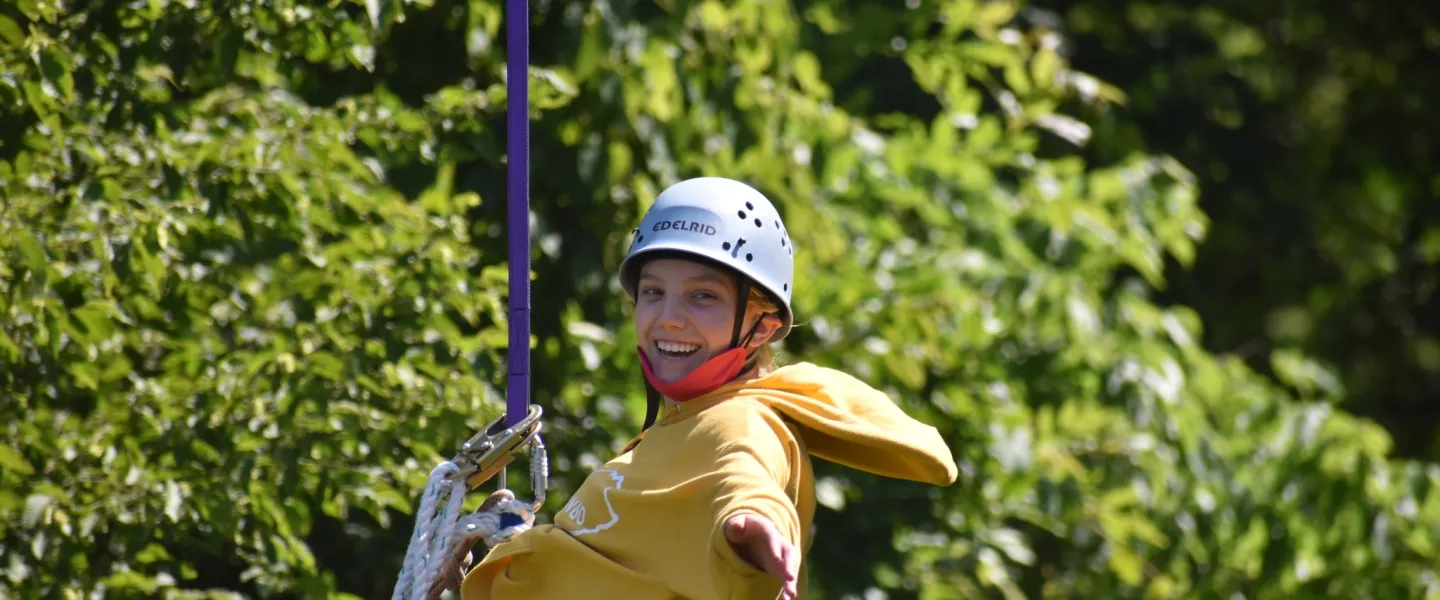 Boy with a yellow sweater and helmet zip lining