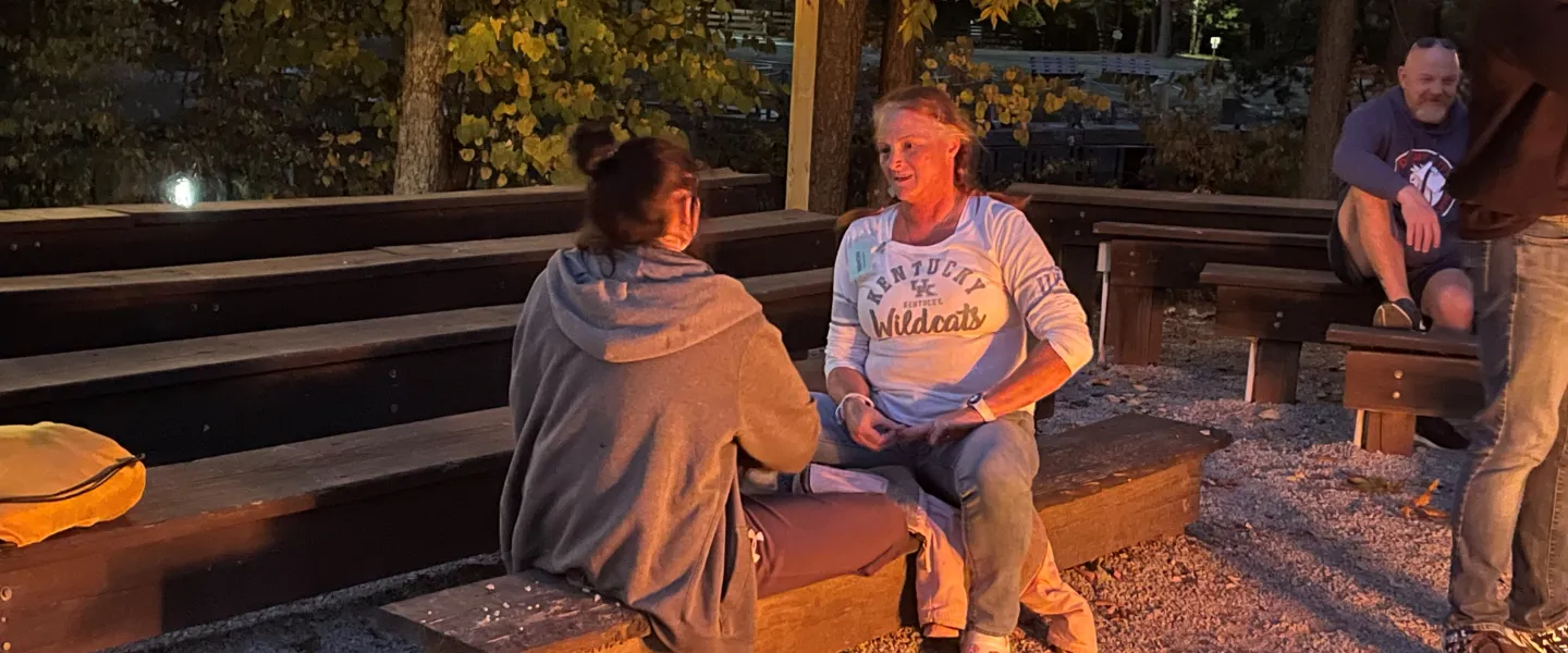 Adult and teen sitting down outside and talking to each other