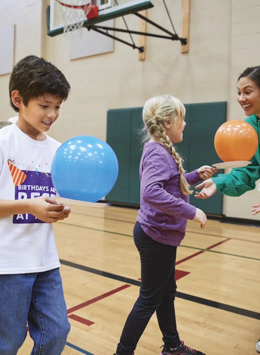 YMCA staff and kids playing with balloons in a gym