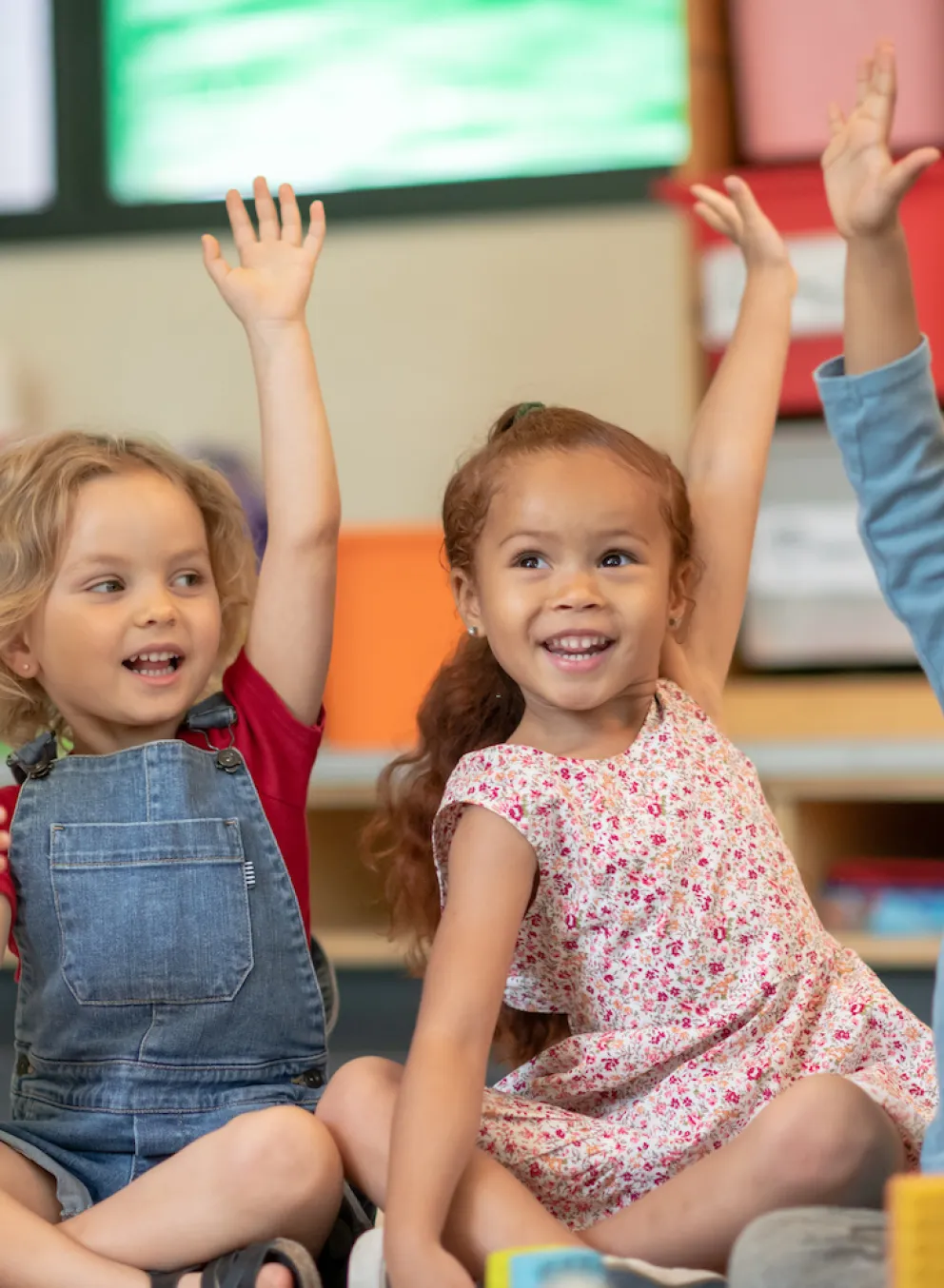 Kids raising their hands in YMCA child care program