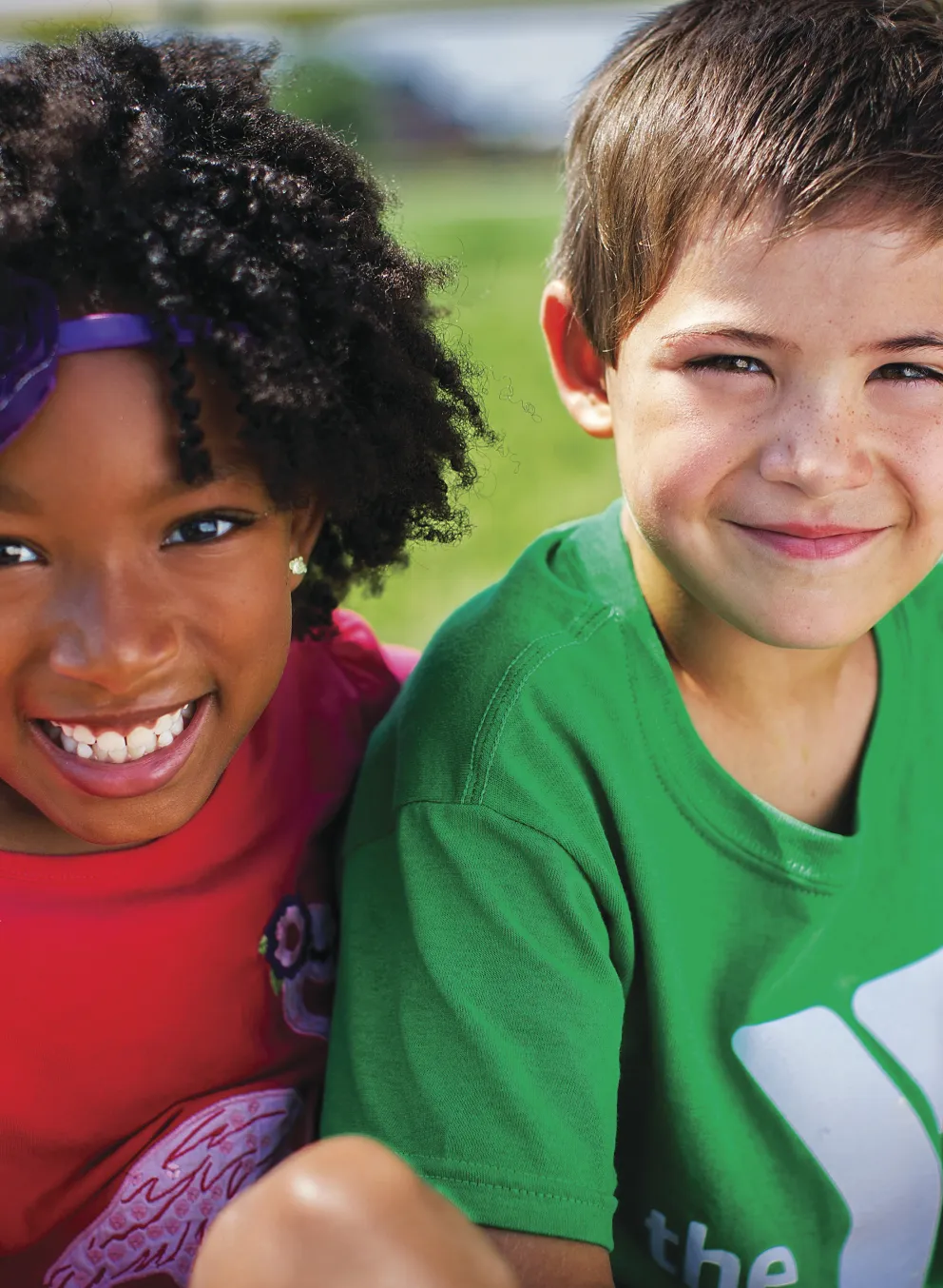 Smiling girl and boy sitting outdoors
