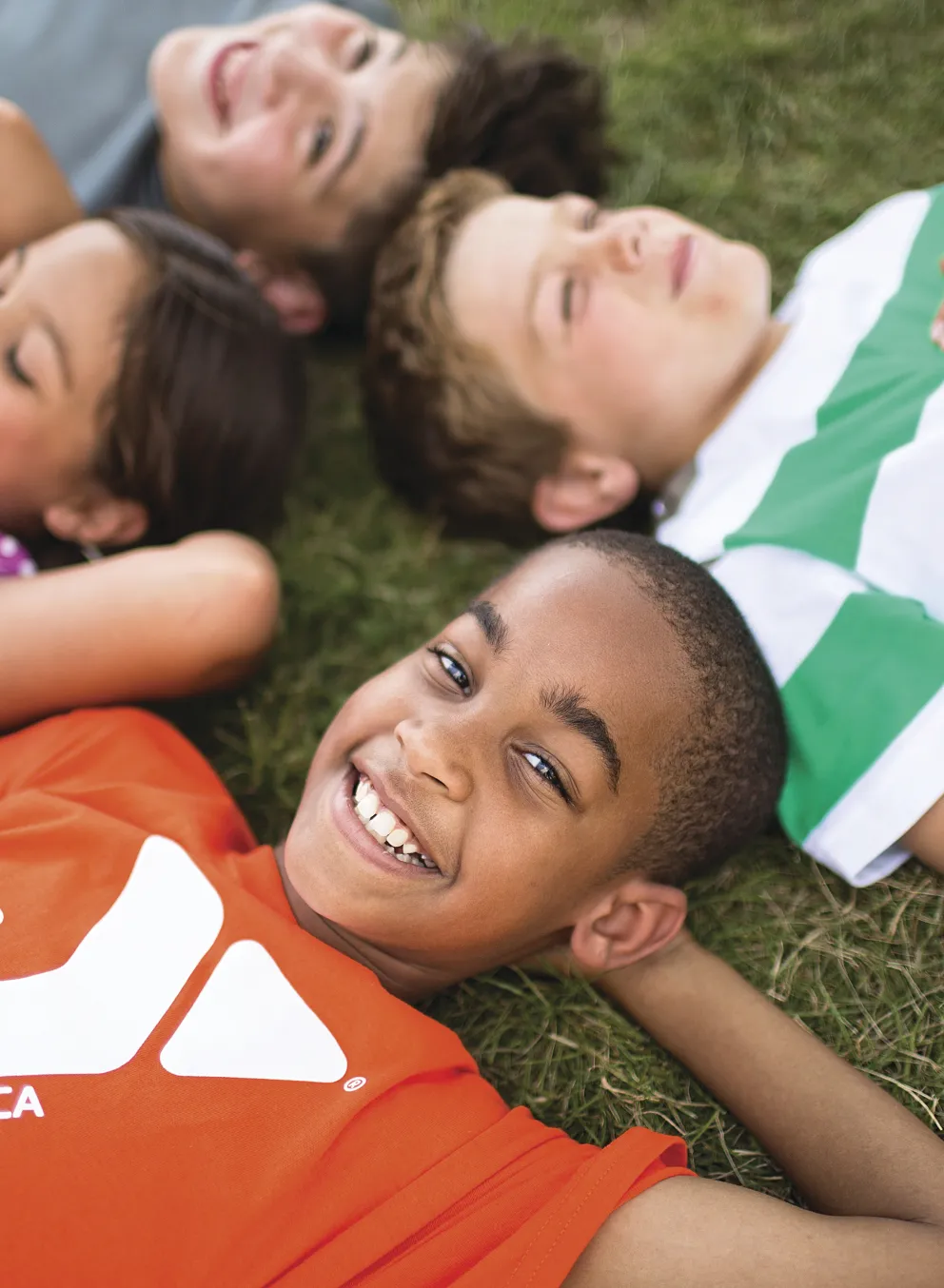 Group of kids laying on the ground looking at clouds