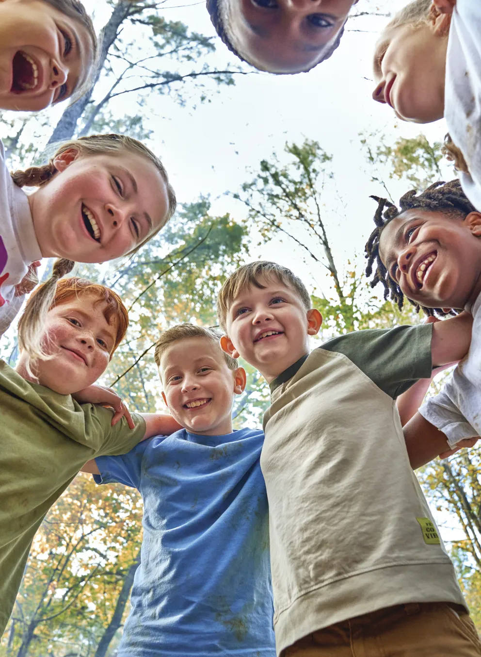 Group of kids outdoors in a circle smiling