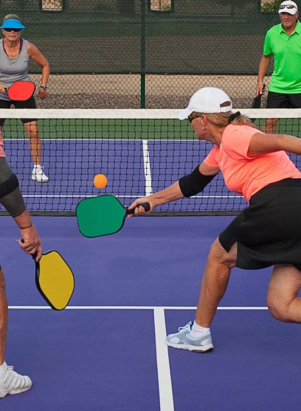 Group of four older adults playing pickleball outdoors