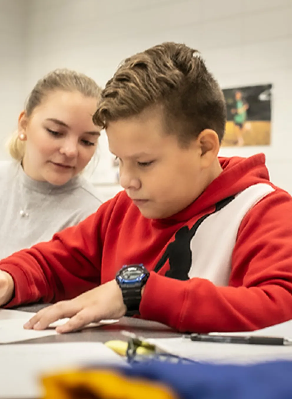 School age boy doing homework as YMCA staff member helps