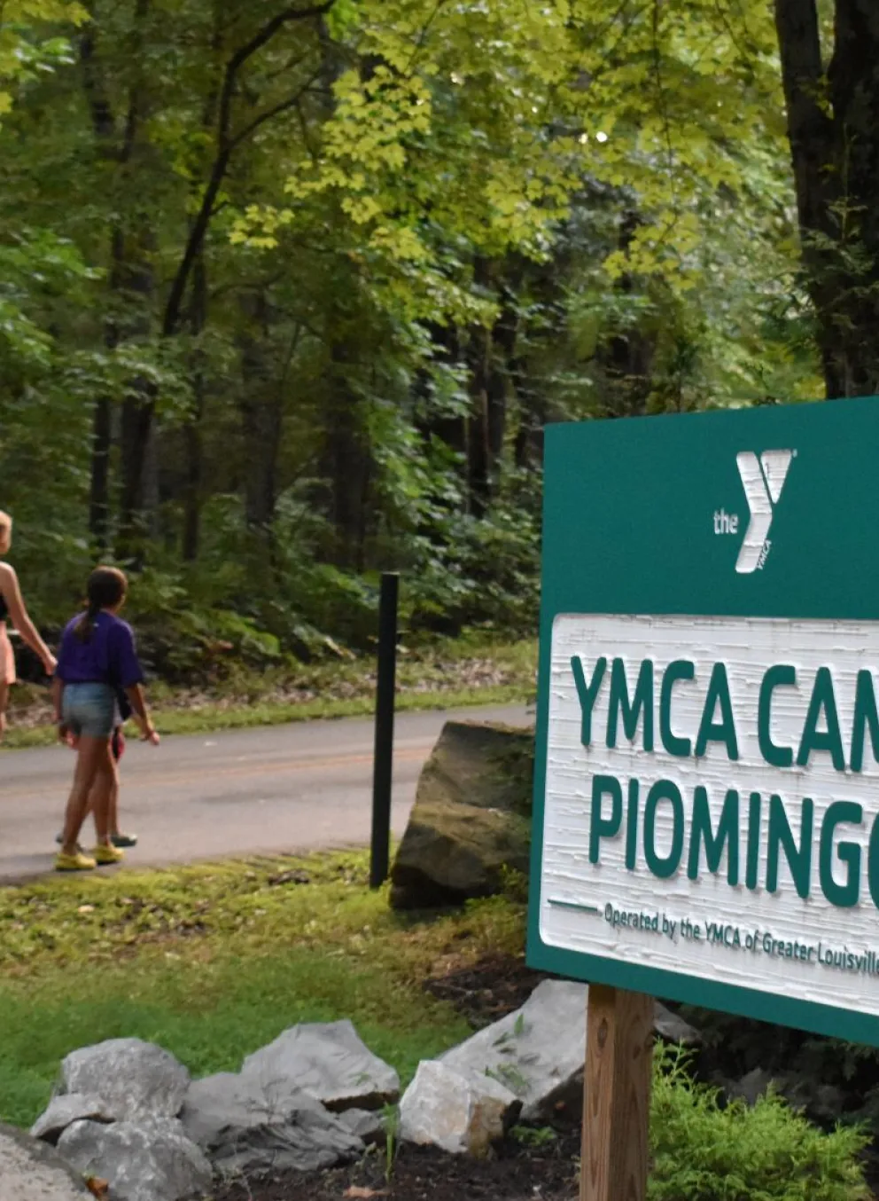 Campers walking past the YMCA Camp Piomingo welcome sign