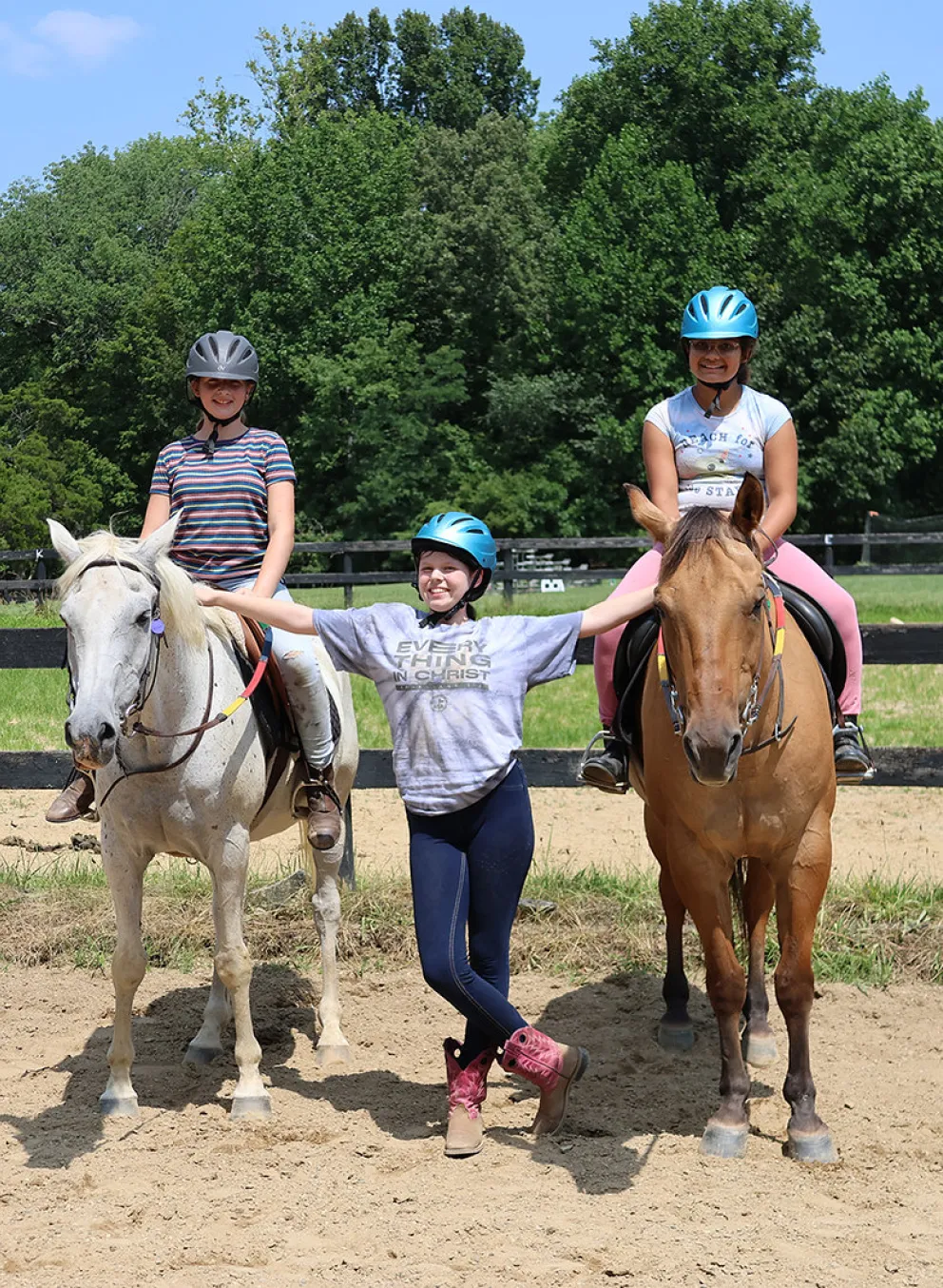 Two girls on horses while another girl is standing next to them