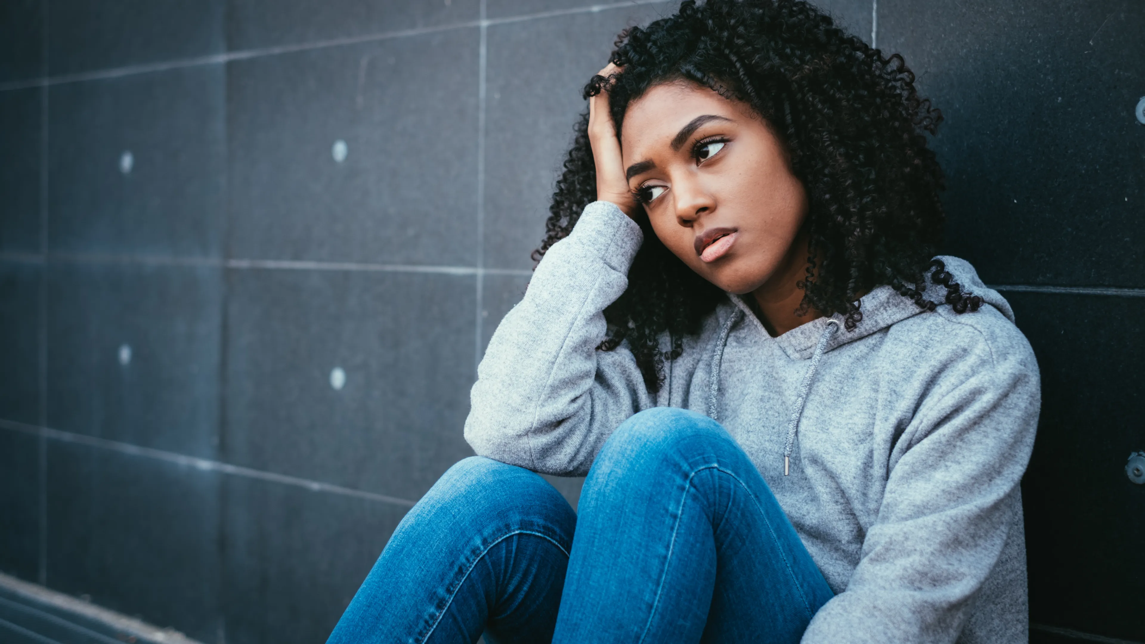 Teen sitting on the floor looking forlorn