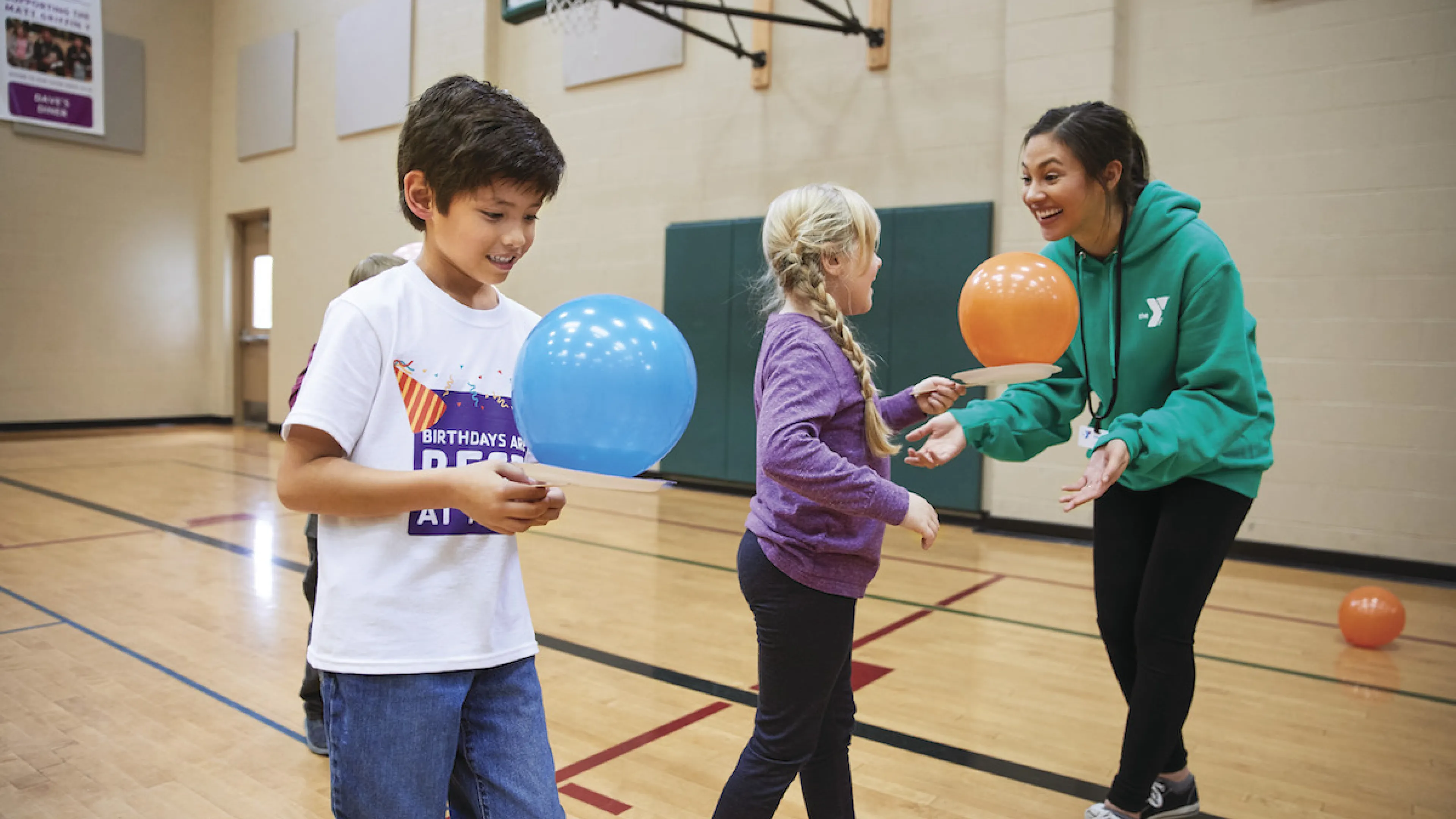 YMCA staff and kids playing with balloons in a gym