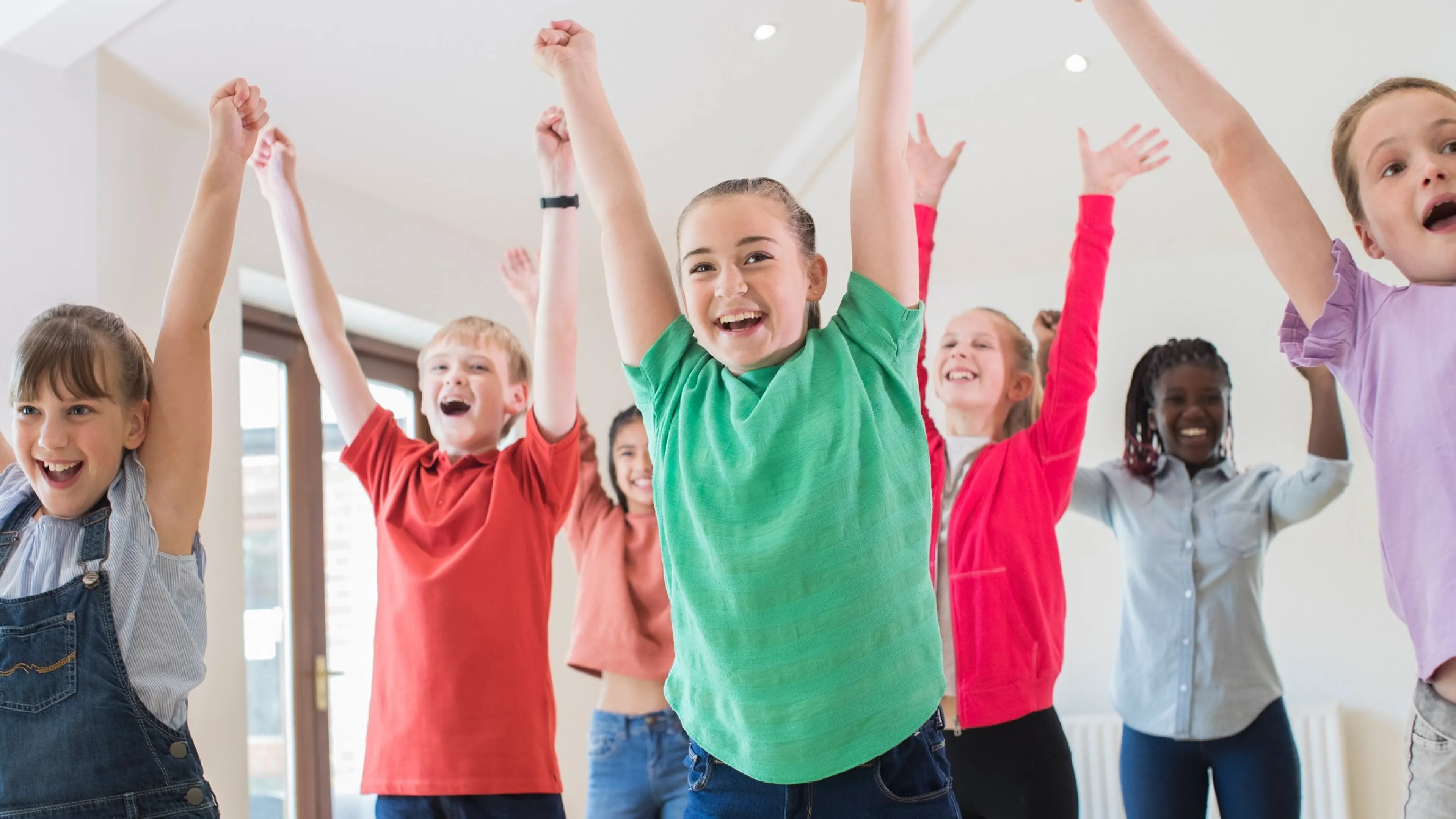 Kids raising hands in the air, celebrating and dancing together