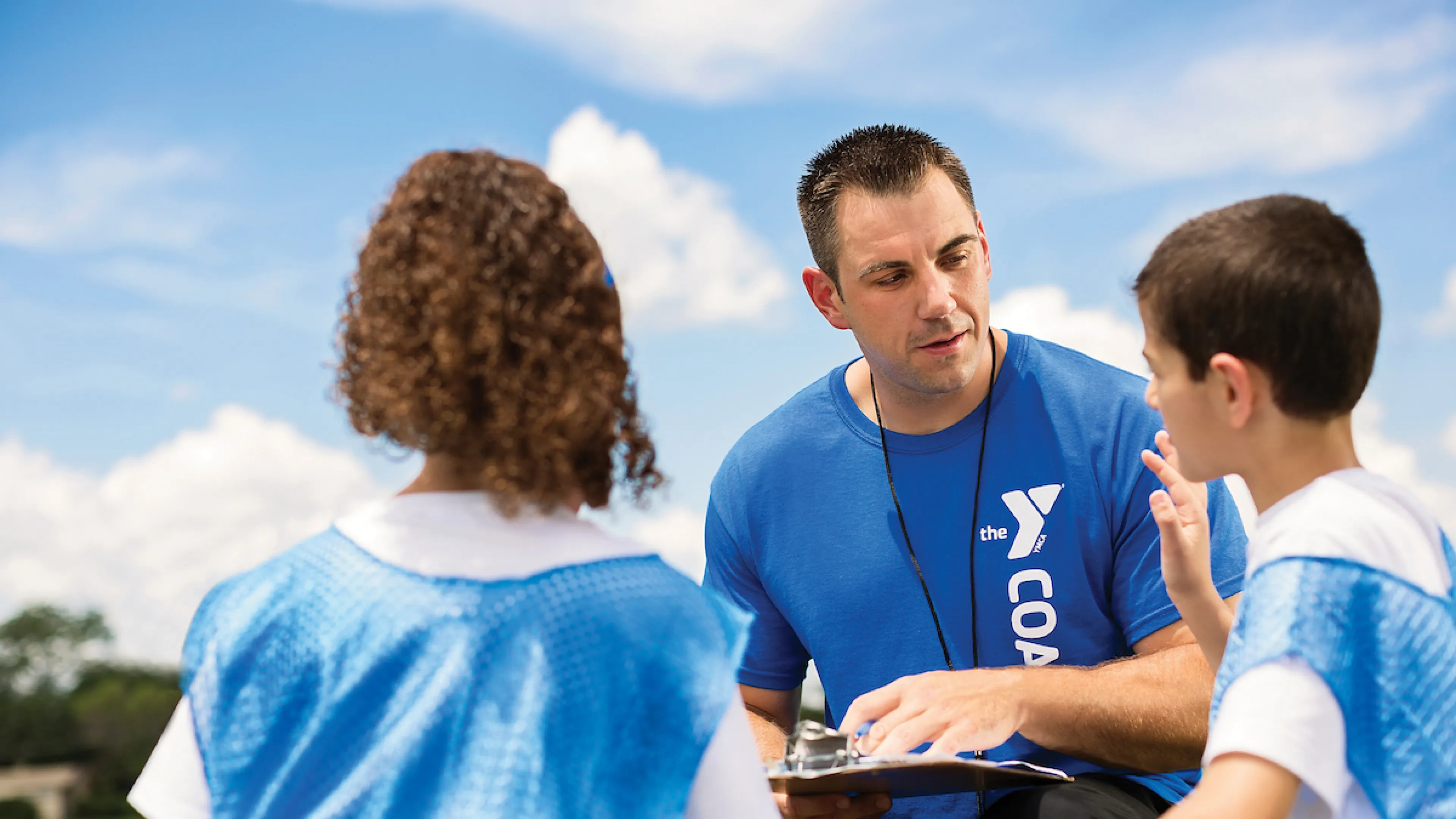 Coach talking to kids for YMCA Louisville youth fitness program