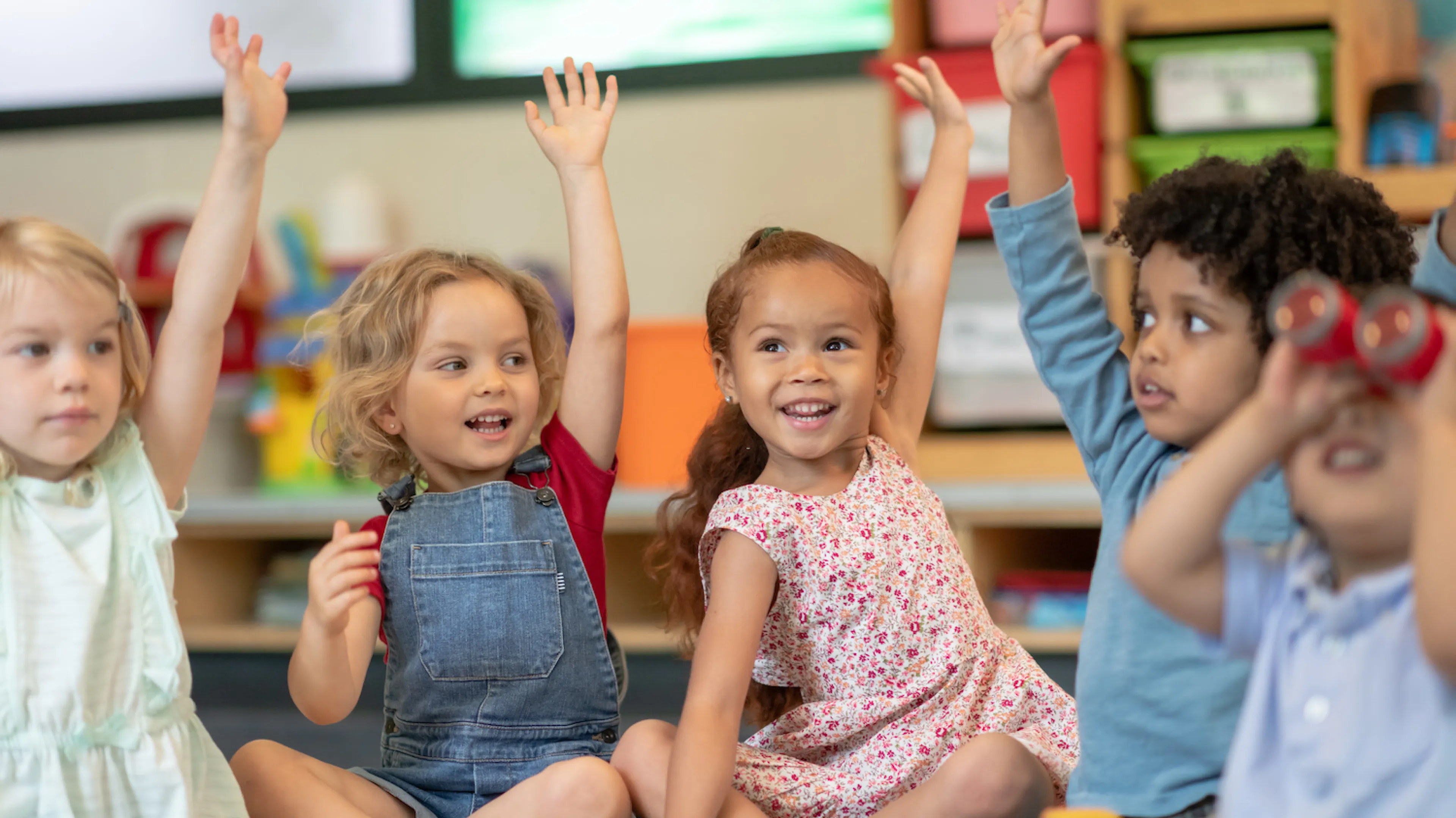 Kids raising their hands in YMCA child care program