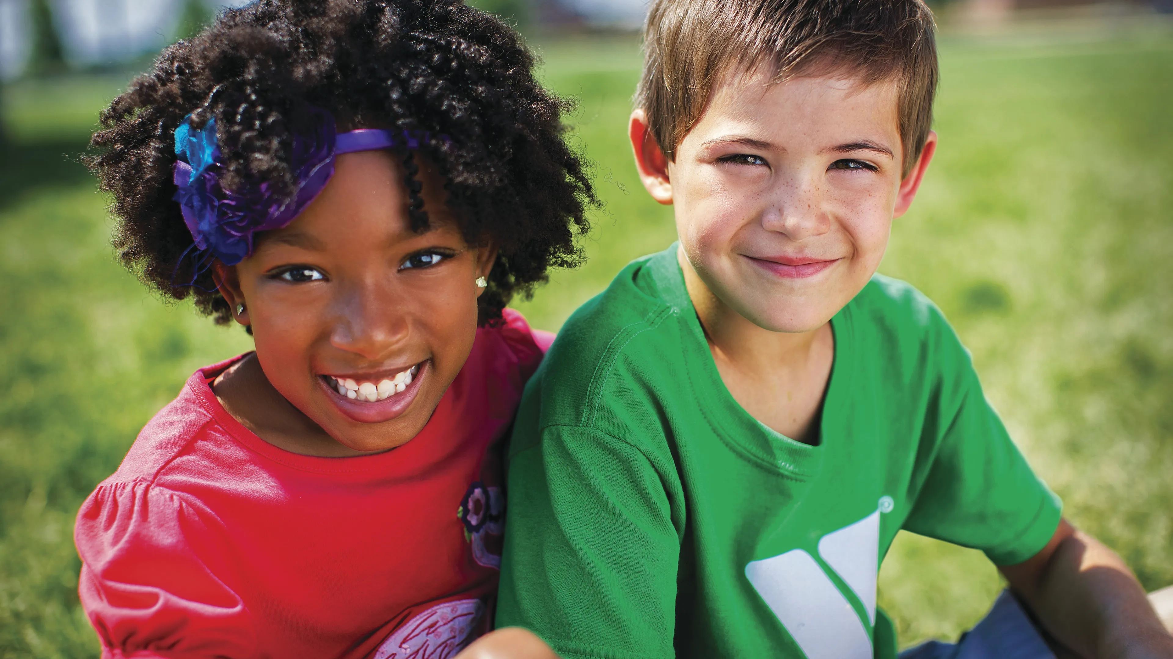 Smiling girl and boy sitting outdoors