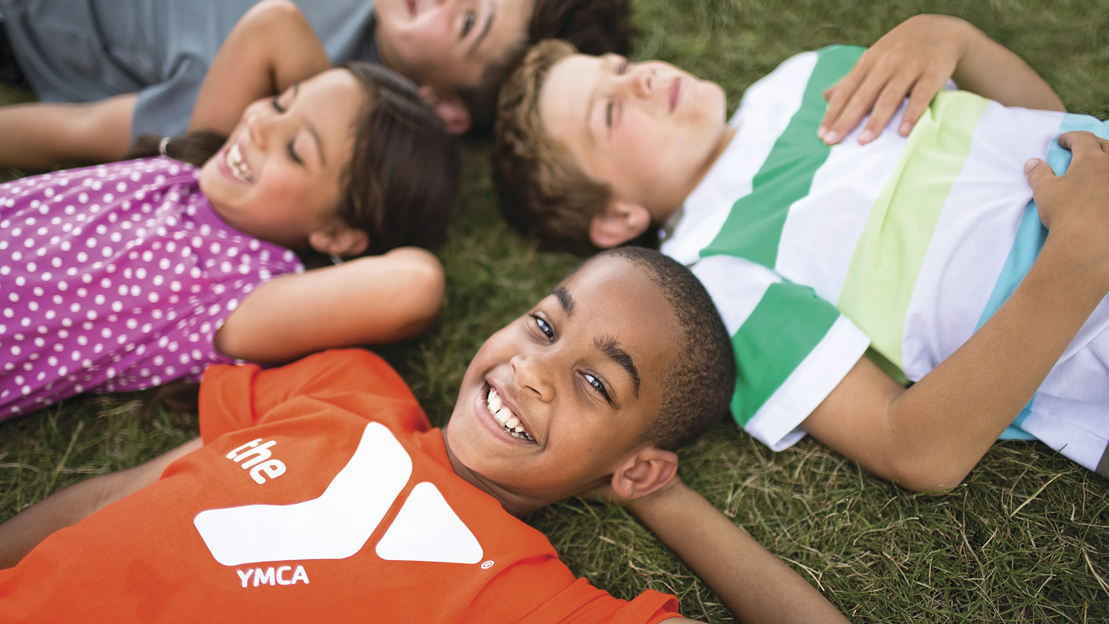 Group of kids laying on the ground looking at clouds