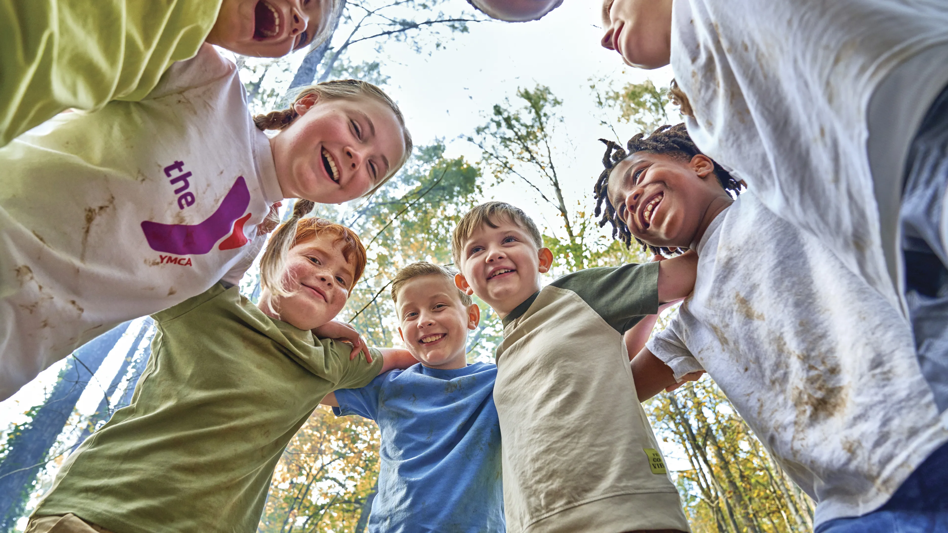 Group of kids outdoors in a circle smiling