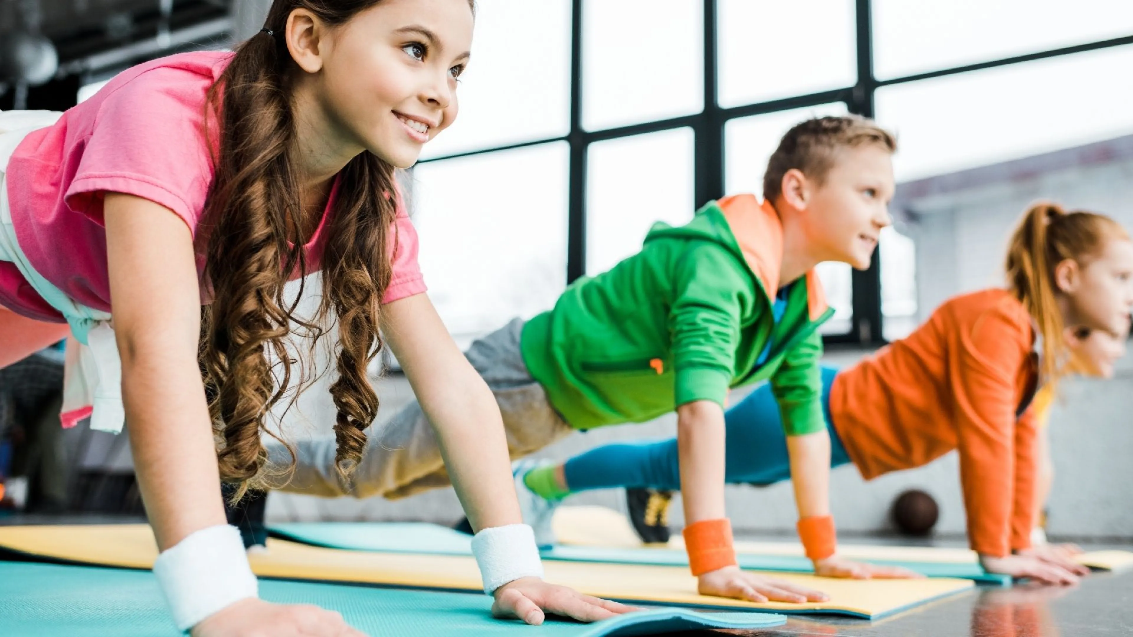 Group of three children smiling and doing push ups