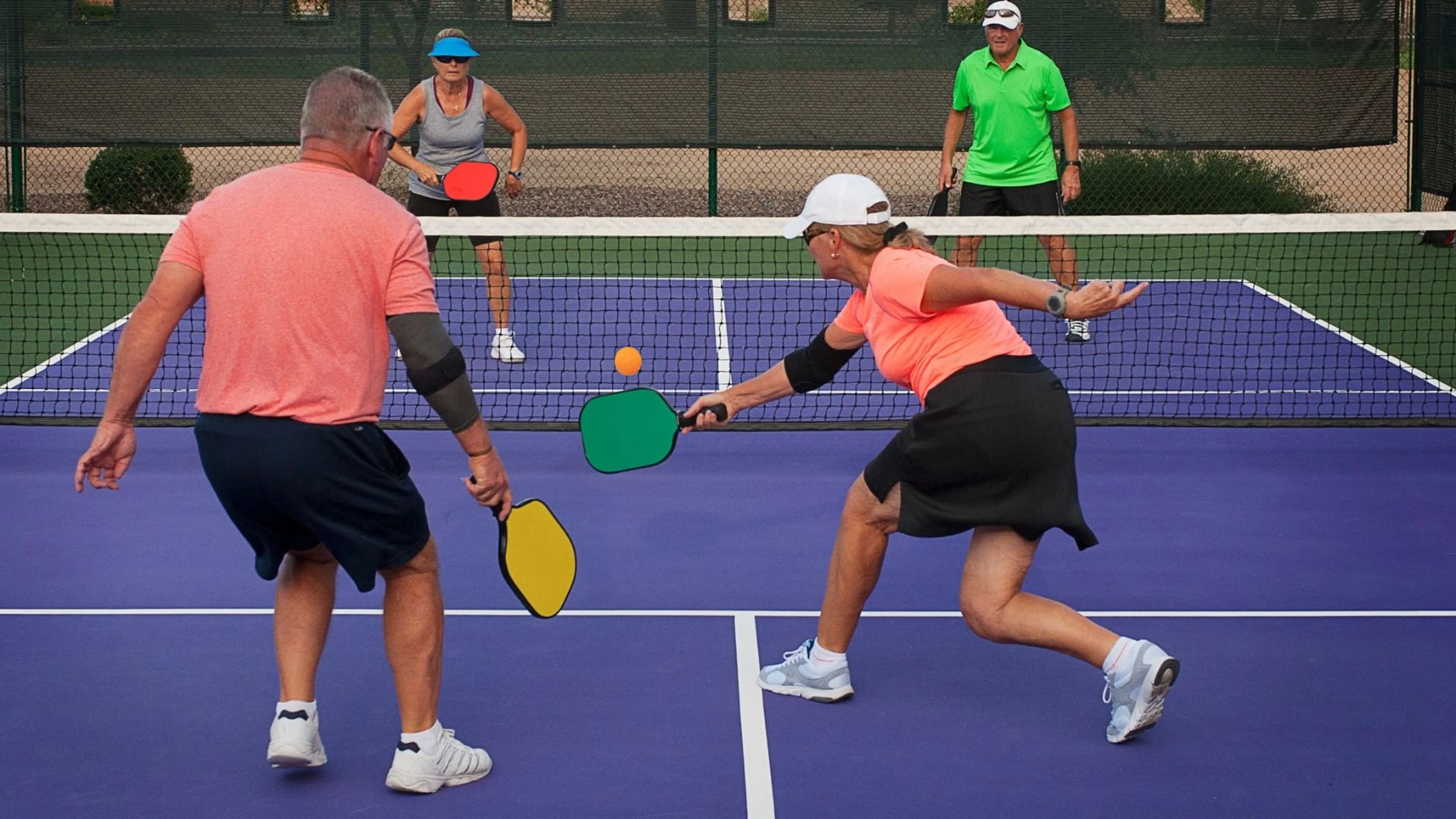 Group of four older adults playing pickleball outdoors