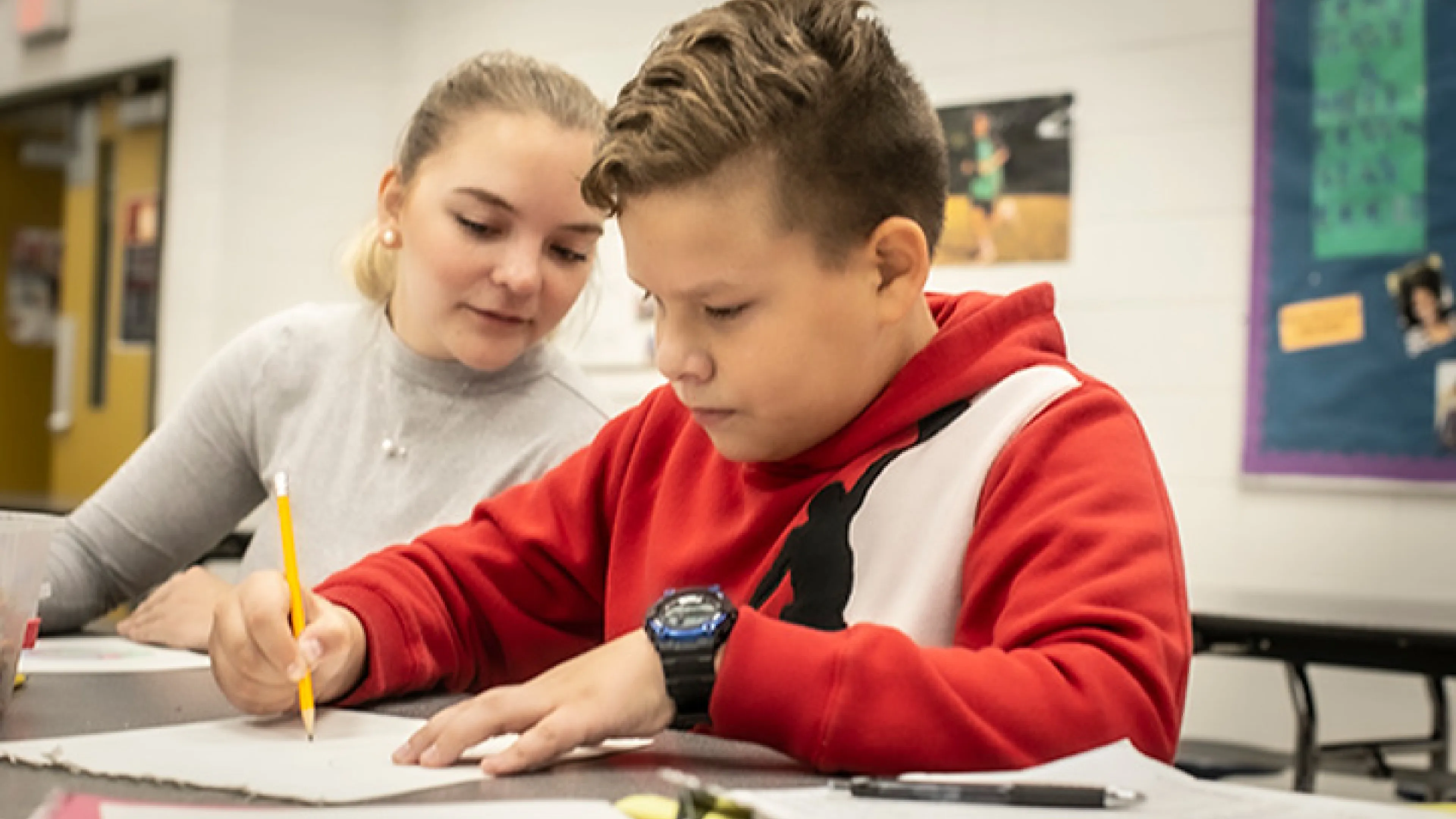 School age boy doing homework as YMCA staff member helps