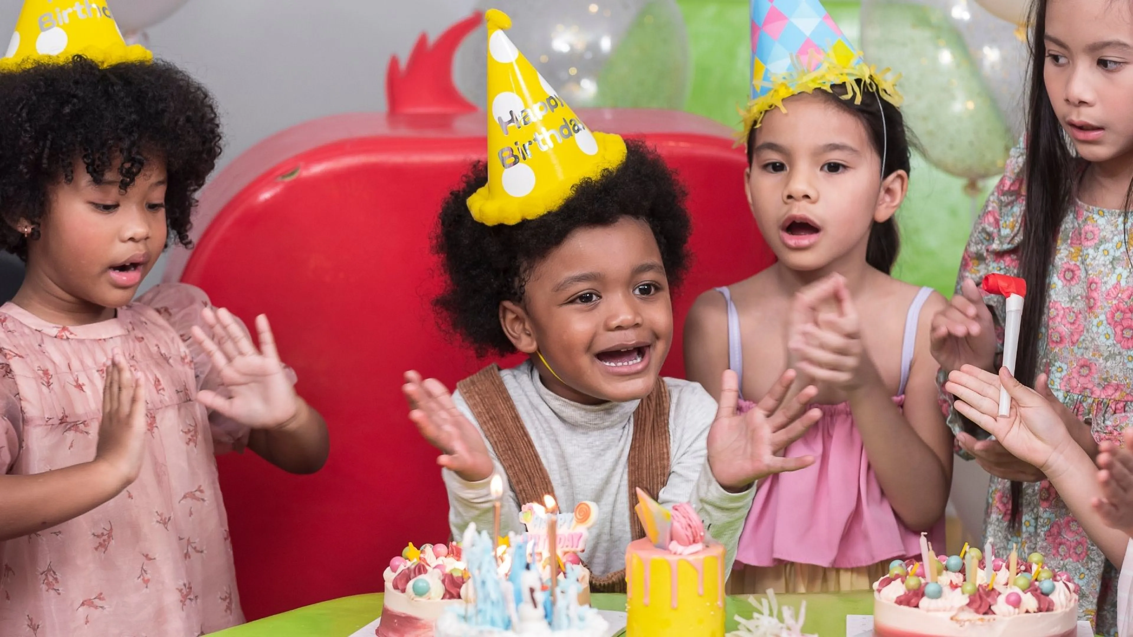 Group of kids in party hats clapping hands