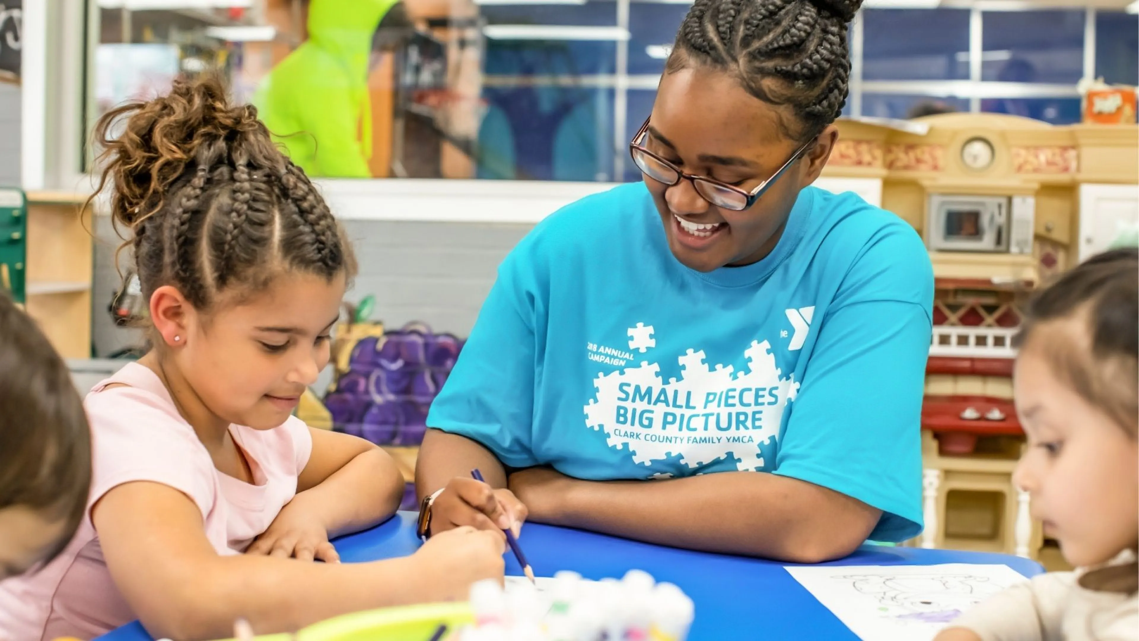 Kids' Club staff member doing crafts with happy young children