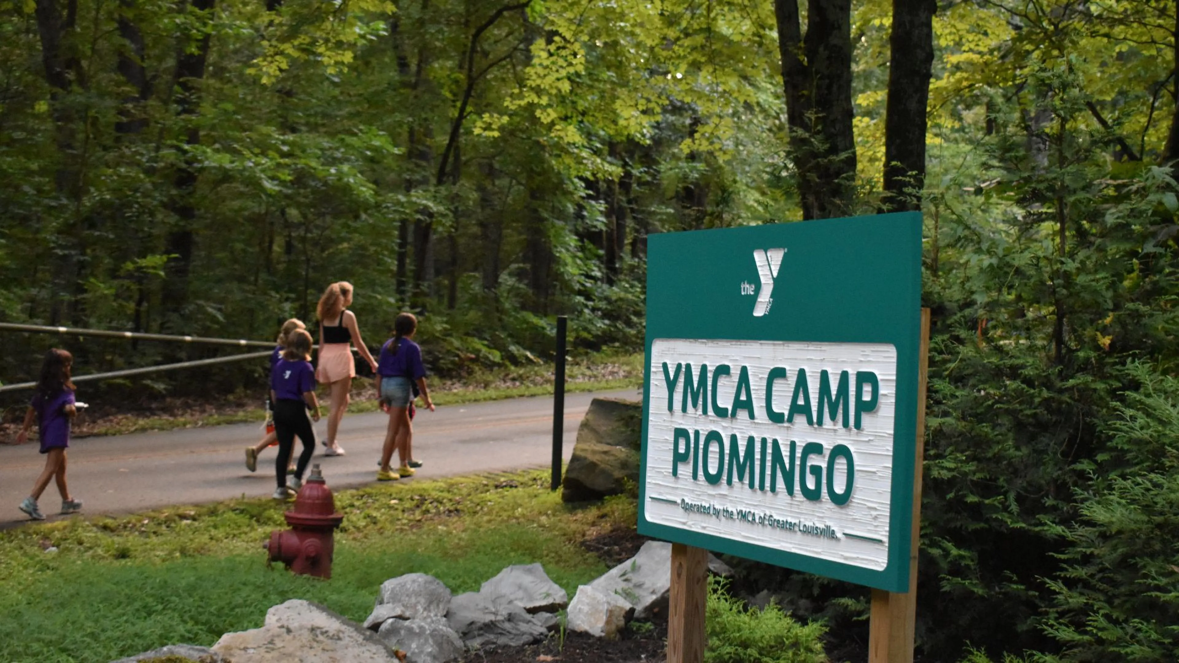 Campers walking past the YMCA Camp Piomingo welcome sign