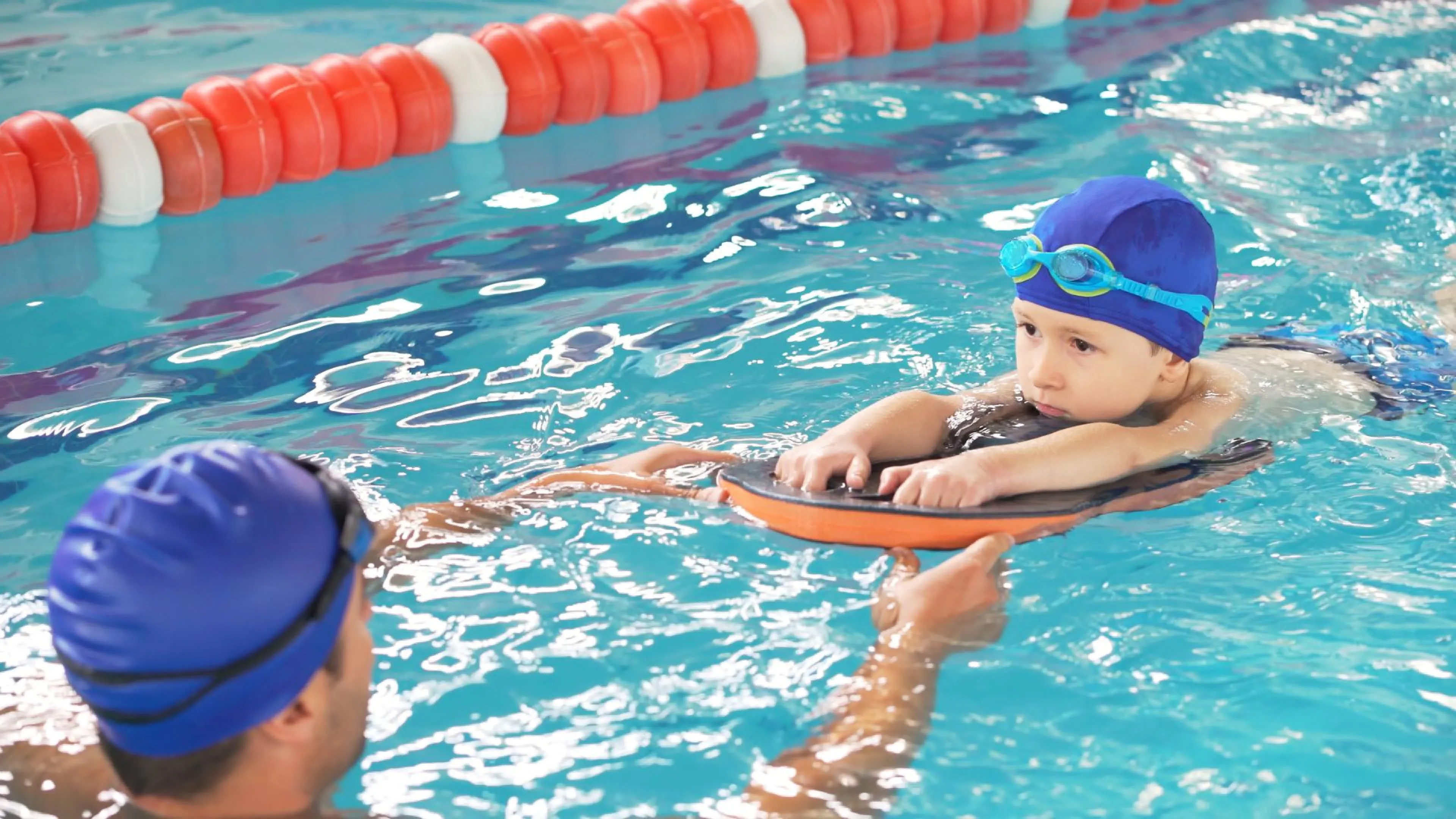 Child in the pool swimming to an instructor