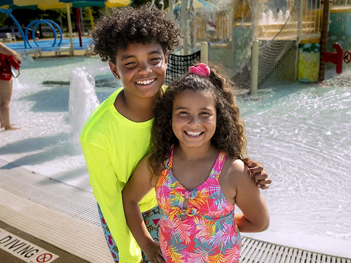 Smiling boy and girl standing next to pool at Calypso Cove Family Waterpark